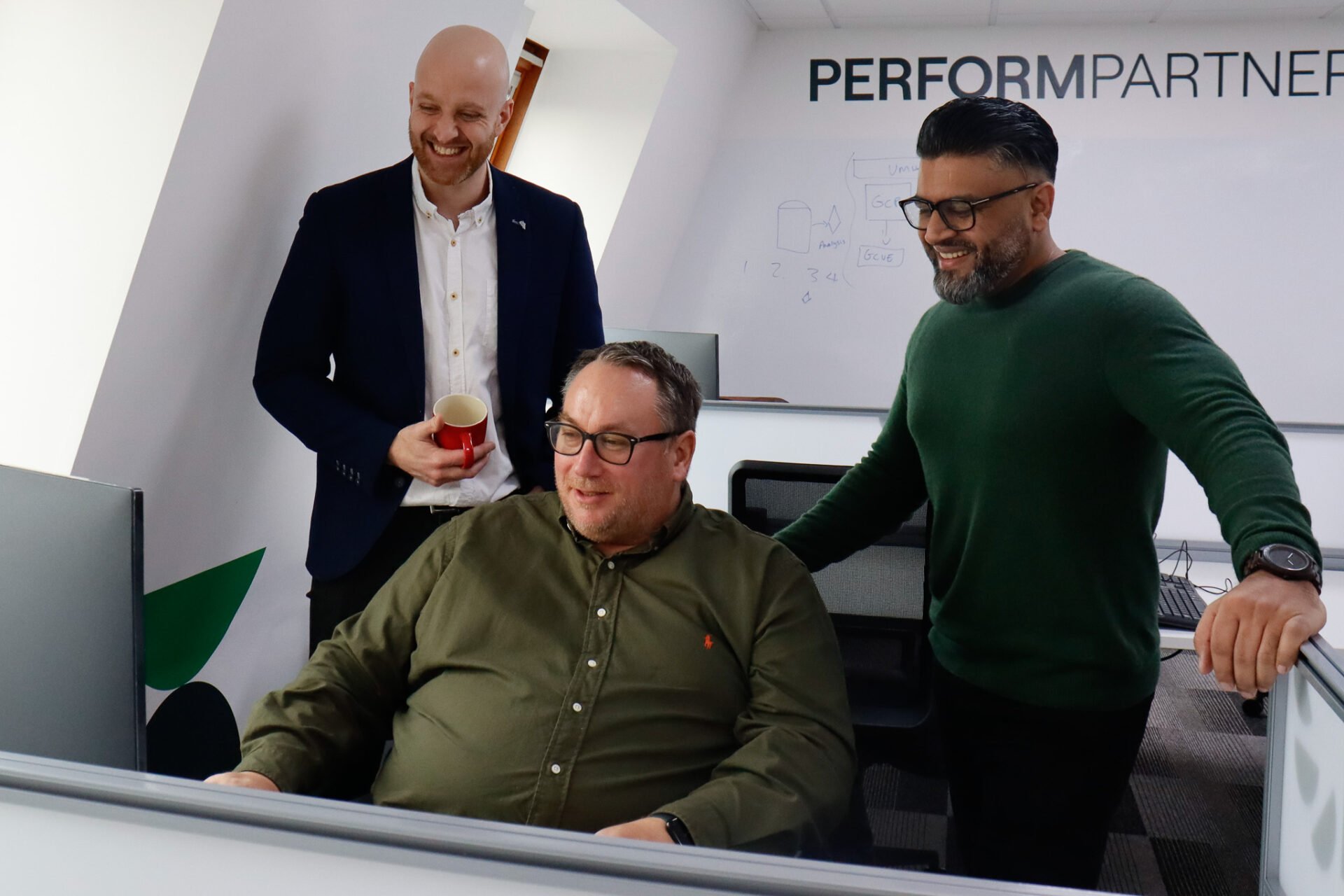 Adeel Azam, Shaun Walsh and David Rush looking at a screen in the Perform Partners' head office.